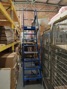 Ladder in between crowded warehouse shelves