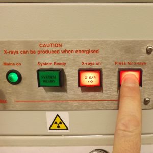 Finger on button marked 'press for x-rays' next to other buttons and indicators